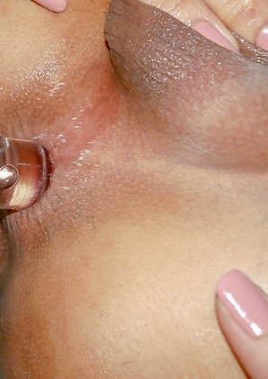 Tall and sexy Ladyboy Swan is sitting on the bed wearing a pink multi-colored blouse, red panties, and flat white sneakers.