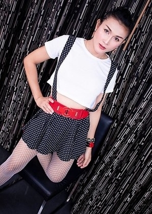 Ladyboy Ice is wearing a skirt with suspender straps over a little white blouse with high heels.