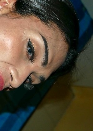 Ladyboy Nokyung is smiling on the bed in a netted pink dress. On her knees, she pulls her dress up to stroke her girl cock with some oil.